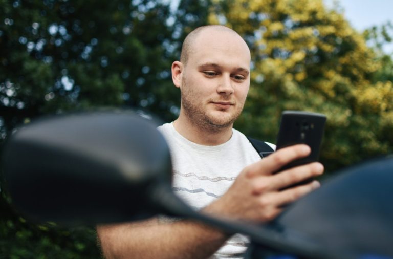 Smiling motorcyclist reviewing insurance coverage on a phone